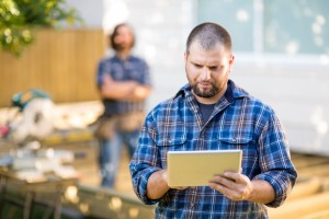 Manual Worker Using Digital Tablet With Coworker Standing In Bac